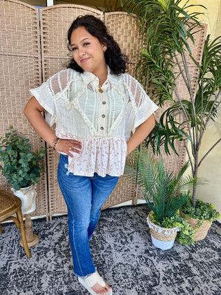 White short-sleeve button-up top with pink floral ruffle hem, worn with blue jeans.
