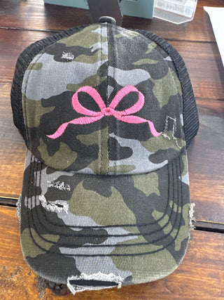 Camo hat with pink embroidered bow, perfect for outdoor adventures. Stylish blend of rugged and feminine details.