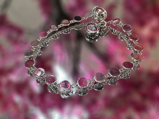Silver bracelet with pink round gemstones and filigree detailing, magnetic closure clasp.
