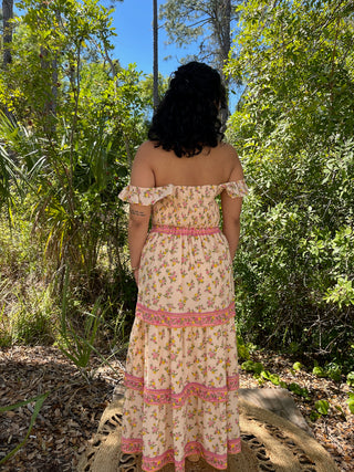 Cream floral off-shoulder maxi dress with pink trim and tiered ruffle skirt.
