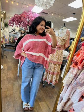 Pink and white striped knit sweater with textured fabric and wavy horizontal stripes.
