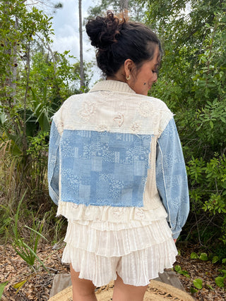 Cream lace jacket with blue patchwork denim back panel and tiered ruffle shorts, back view.
