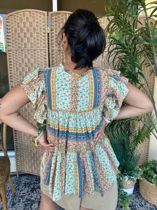Turquoise floral patchwork top with ruffled flutter sleeves and tiered ruffle hem detail.
