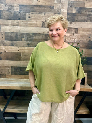 Olive green short-sleeve oversize knit sweater with boatneck neckline on model.

