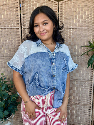 Blue denim shirt with embroidered white stars on shoulders and distressed details, short sleeves.
