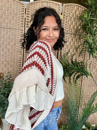 Cream and burgundy striped knit shawl draping over white ribbed tank top.
