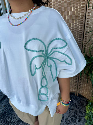 White oversized tee with green rope-textured palm tree graphic on chest.
