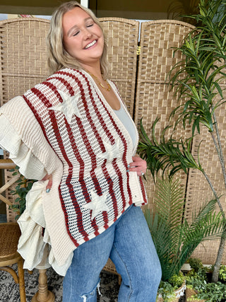 Red and white striped crochet cardigan with ruffled edges over white top and blue jeans.
