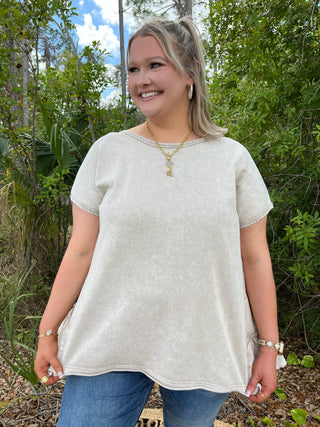 Ecru linen short-sleeve top with ruffle hem detail, relaxed fit.
