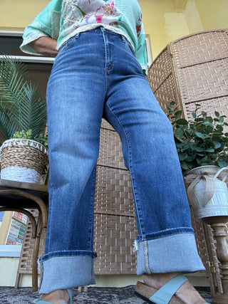 High-rise relaxed fit blue jeans with rolled cuff hem, worn with turquoise floral top.
