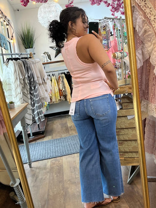 Blush pink ribbed knit tank top with scoop neckline on model wearing blue jeans.
