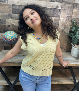 Butter yellow open knit v-neck sleeveless sweater vest with textured pattern detail.
