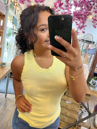 Yellow ribbed knit tank top with crew neckline shown on model in store setting.
