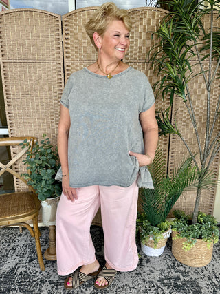 Gray short-sleeve t-shirt with ruffle hem detail paired with pink pants.
