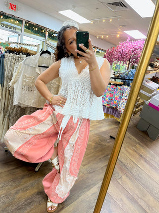 White textured sleeveless V-neck top with ruched fabric detail on model in dressing room.
