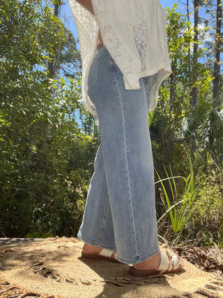 Wide-leg blue jeans with center seam detail paired with cream lace button-up shirt.
