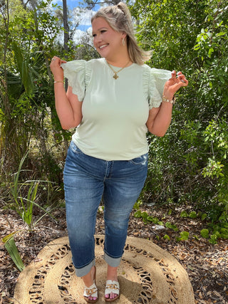 Cream short-sleeve top with ruched eyelet flutter sleeves and crew neckline.
