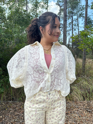Ivory lace eyelet blouse with short puffed sleeves and button front, paired with cream floral pants.
