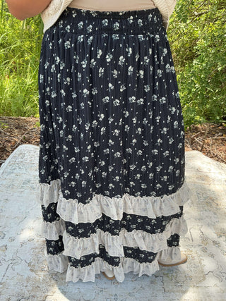 Navy floral maxi skirt with ivory ruffles, featuring a flowing design and elegant pattern.