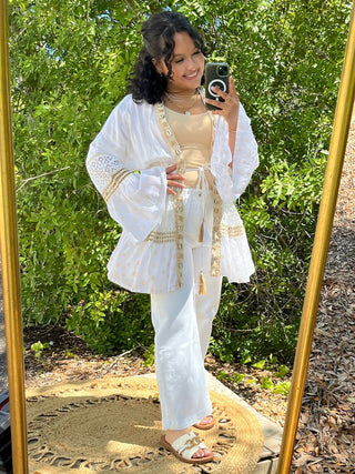 Ivory linen kimono with lace sleeves and tassel tie belt worn over cream camisole and white pants.
