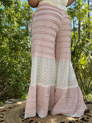 Pink ruched tiered pants with eyelet embroidery and lace trim details.
