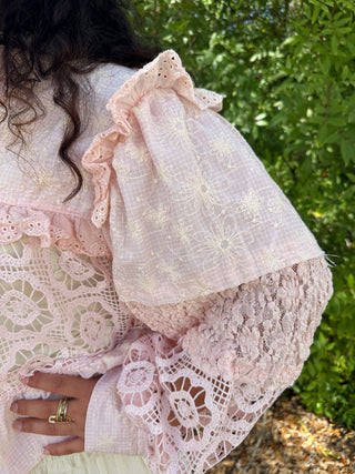 Blush pink shacket with embroidered daisy flowers, lace trim, and ruffled collar detail.
