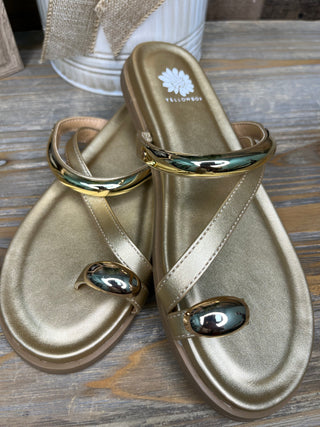 Gold metallic thong sandals with gold toe ring hardware and white strap details.
