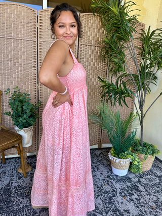 Pink eyelet halter jumpsuit with intricate cutout pattern and flowing wide-leg silhouette.

