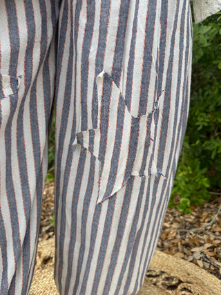 Blue and white striped jogger pants with distressed rips on the thigh.
