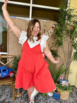 Red denim romper with white eyelet collar and ruffled cap sleeves.