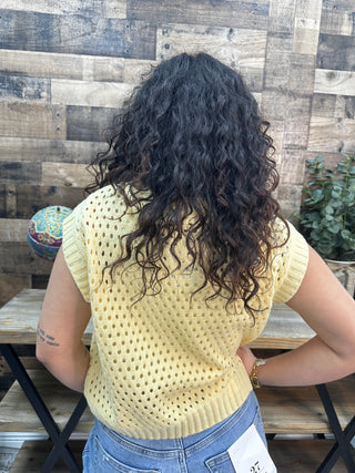 Butter yellow open knit sweater vest with v-neckline and short sleeves displayed on model from back.
