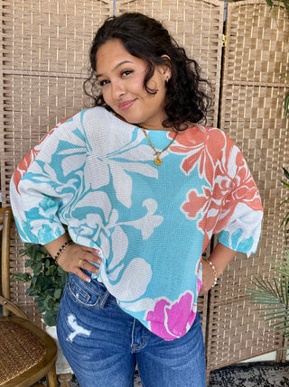Coral Reef Batwing Top in turquoise, coral, and white with abstract floral pattern and short wide sleeves.
