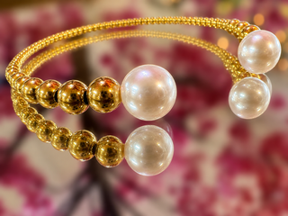 Gold mesh bangle bracelet with pearl and gold beads, adjustable cuff design.
