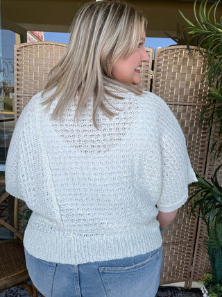 Cream knit sweater with openwork texture and short puffed sleeves on model.
