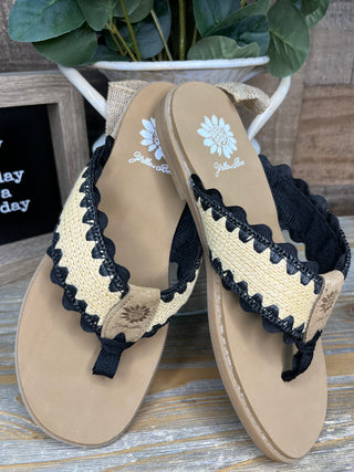Beige flip-flop sandals with black and cream ricrac trim and black straps, displayed from above.
