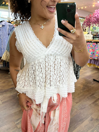 White lace V-neck sleeveless top with textured fabric and scalloped hem detail.
