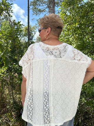 White lace short-sleeve top with floral crochet yoke and geometric pattern panels down back.
