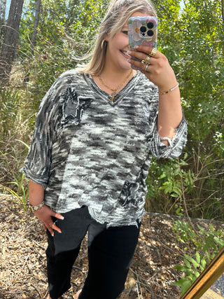 Charcoal and white slub knit top with star patch detail and distressed edges, v-neckline.
