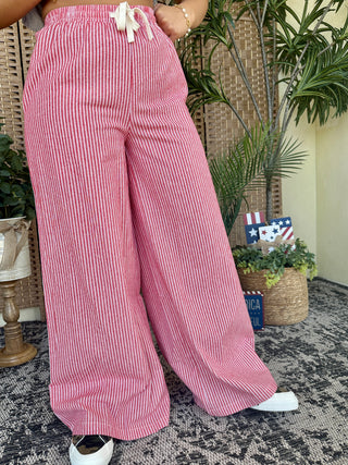 Red and white striped wide-leg pants with elastic waist and drawstring tie detail.
