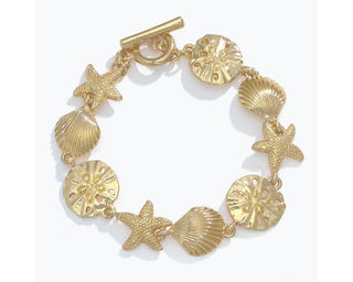 Gold bracelet with alternating starfish, shell, and sand dollar charms with toggle clasp.
