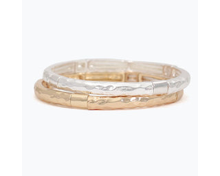 Stacked silver and gold hammered bangle bracelets with textured finish.
