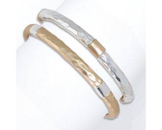 Two hammered metal bangle bracelets in gold and silver with curved handles stacked together.

