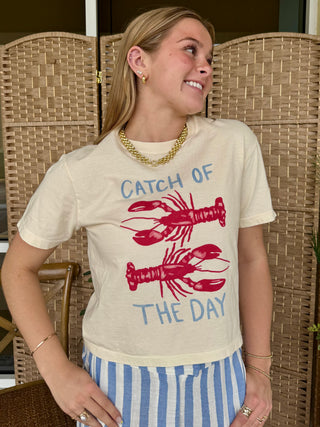 Cream graphic tee with "Catch of the Day" text and red lobster illustrations.
