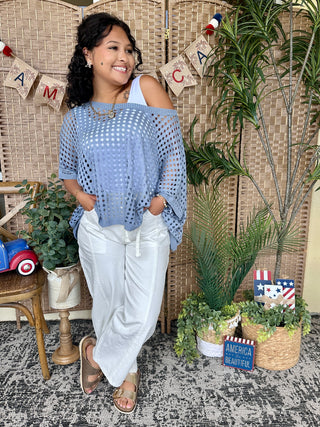 Periwinkle blue dolman top with eyelet cutout pattern and cold-shoulder neckline.
