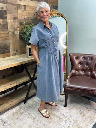 Light blue mineral-washed denim button-down midi dress with short sleeves and pleated skirt.

