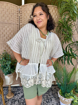 Gray striped kimono top with white eyelet ruffled hem and tie front detail.