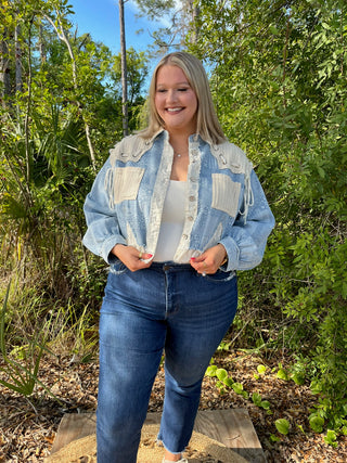 Light blue and cream patchwork denim jacket with chest pockets over white tank top and dark jeans.
