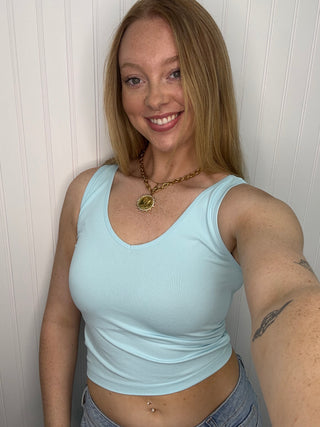Light blue seamless tank top with scoop neckline and ruched side detail on model.
