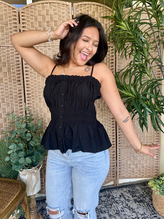 Black smocked camisole top with button details and tiered ruffle hem.
