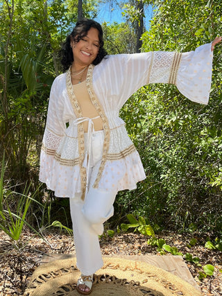 Ivory linen kimono with lace trim and gold embroidered details, bell sleeves, tie-front closure.
